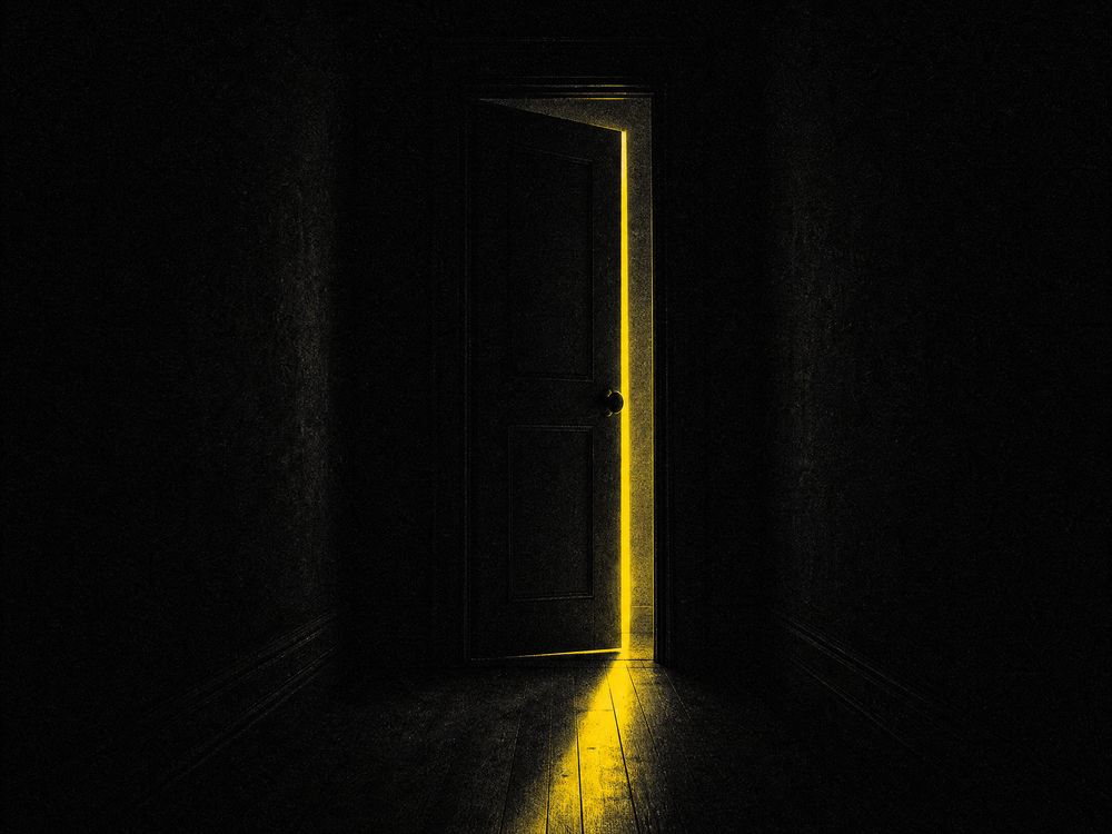 A narrow corridor in harsh monochrome with a single yellow emergency lamp at the far end